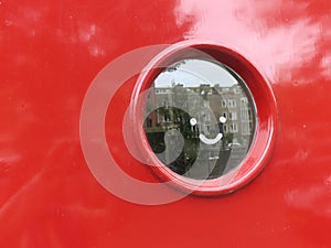 Looking hole: smile on a round window in a red frontdoor