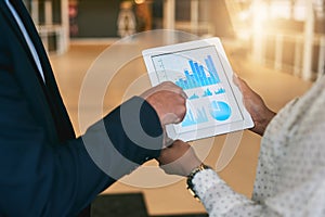 Looking at the latest reports. Closeup shot of two unrecognisable businesspeople analysing graphs on a digital tablet in