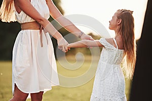 Looking at mother with love. Woman and her daughter enjoying weekend together by walking outdoors in the field