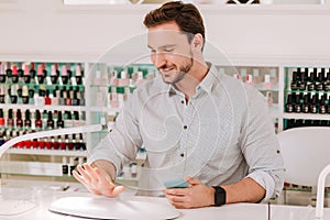 Metrosexual man looking at his nails after getting manicure