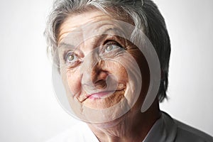 Looking old woman portrait on a grey