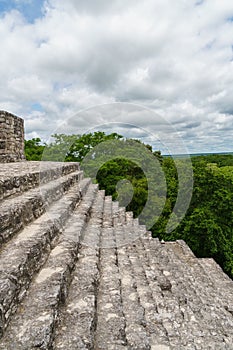Looking out across ancient Mayan stone steps towards the jungle canopy and sky in Calakmul, Mexico