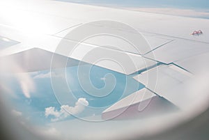 Looking out through airplane window view photo showing its wing and blue sky, travelling photo