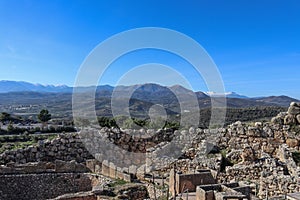 Looking out over the hill fort at Mycenae Greece and the museum and parking lot and over farmland and olive groves to the
