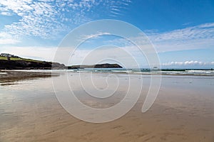 Looking out over the sandy beach at Polzeath in Cornwall, with a blue sky overhead