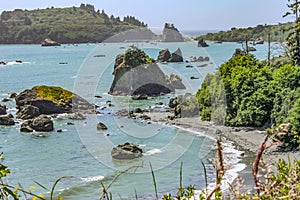 Looking out over Trinidad Bay in Northern California at the beach below with rocks jutting out of the ocean and misty outcroppings photo