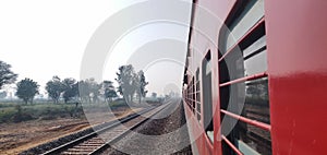 Looking out of the window of a express train of Indian railways with a view of green farm lands