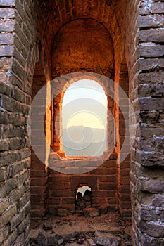 Looking out the window of guard tower during a sunset on the unrestored great wall of China
