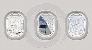Looking out the windows of a plane to the aircraft wing and clou
