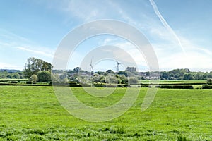 Looking over green farming fields towards the town of Dreghorn in the far distance on a bright spring day in May