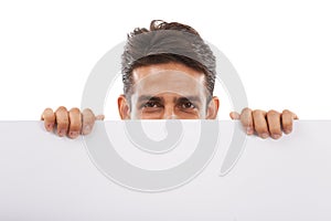 Looking over your copyspace. Portrait of a handsome young man peeping over the top of a blank billboard.