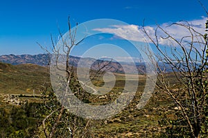 Looking own on hilly rocky terrain and road and moutains in the distance in the Idaho highlands