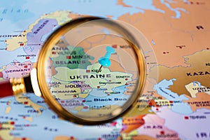 Looking at pinned Ukraine on map of Europe through magnifier. International relationships