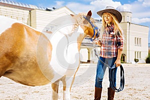 Cute appealing schoolgirl looking at little brown pony