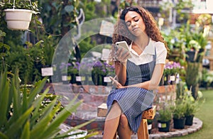 Looking for somebudy to love. a young florist using her smartphone to send a text.