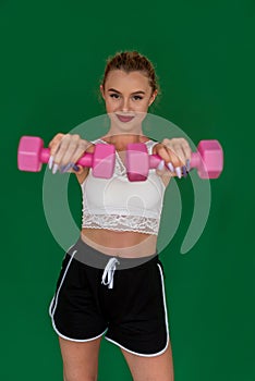 looking straight at a girl posing for the camera with dumbbells in each hand.