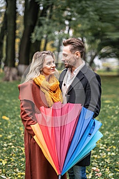 Looking in to the eyes of each other with closed rainbow umbrella beautiful in love couple standing in the park under a