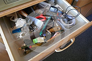 Looking into a untidy drawer.  Messy drawer with tools, household items and various other objects