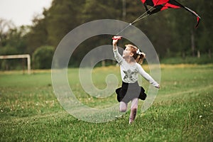 Looking up. Amazing weather. Happy girl in casual clothes running with kite in the field. Beautiful nature