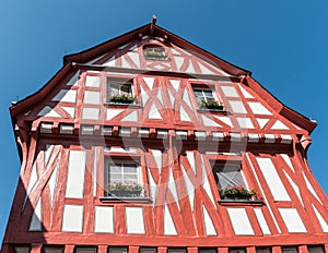 Looking up at an ancient half timbered house in Boppard, Germany, showing its bright decoration contrasted against a deep blue sky