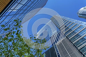 Looking up at apartments exterior with glass windows reflecting the blue sky