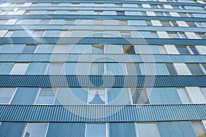 Looking up a blue and tall apartment building..