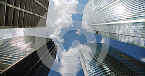 Looking up at business skyscrapers buildings in dowmtown, clouds rolling in sky and reflections on glass. 4k