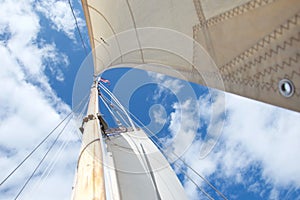 Looking up the mast on a sailing yacht, focussed on the flag at the masthead