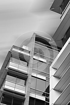 Looking up at modern office building against smooth cloudy sky