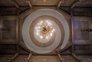Looking up at old church ceiling. Chandelier light and classic i