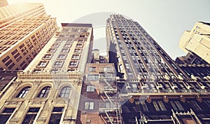 Looking up at old Manhattan buildings against the sun, color toned picture, New York City, USA