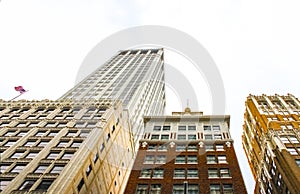 Looking up at ornate art deco buildings with an American flag flying on one