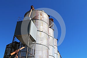 Looking up at a rusty old working agricultural feed grain and corn silo building against a blue sky in rural heartland america