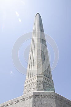 Looking up at the San Jacinto Monument with a dazzling sun behind it, and a clear blue sky