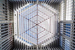 Looking up at the skylight glass roof of an atrium, with geometric structure in modern contemporary architectural style