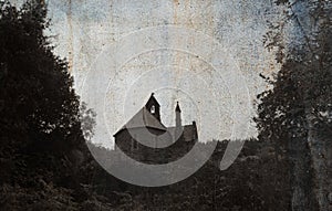 Looking up at a spooky church surrounded by trees in the countryside with a moody, vintage, grunge edit