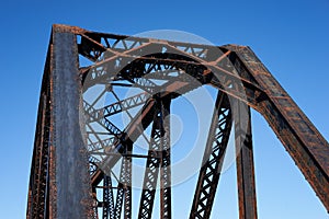 Looking up at a steel train bridge structure