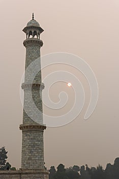 Looking up at the Taj Mahal in Agra, India, on overcast morning with small red sun