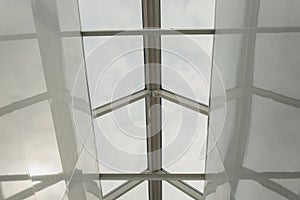 Looking up to the blue cloudy sky through modern square ceiling window.