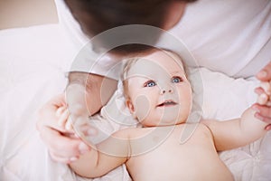 Looking up to her Dad. a devoted young dad holding onto his baby daughters hands.