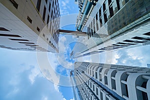 Looking up to high-rise office buildings, skyscrapers, architectures in financial district with blue sky. Smart urban city for