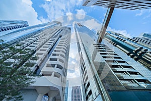 Looking up to high-rise office buildings, skyscrapers, architectures in financial district with blue sky. Smart urban city for