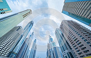 Looking up to high-rise office buildings, skyscrapers, architectures in financial district with blue sky. Smart urban city for