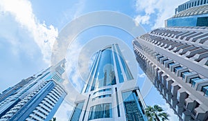 Looking up to high-rise office buildings, skyscrapers, architectures in financial district with blue sky. Smart urban city for