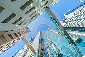 Looking up to high-rise office buildings, skyscrapers, architectures in financial district with blue sky. Smart urban city for