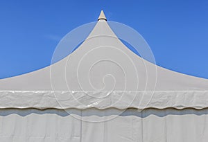 Looking up at the top of white tent with blue sky background