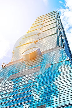 Looking up view of Taipei 101, the landmark of Taiwan, reflect blue sky and sun lights