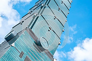 Looking up view of Taipei 101, the landmark of Taiwan, reflect blue sky and sun lights