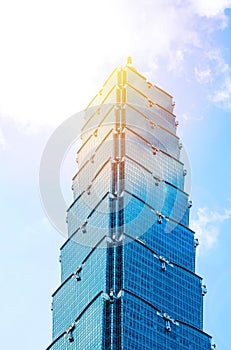 Looking up view of Taipei 101, the landmark of Taiwan, reflect blue sky and sun lights