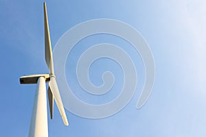Looking up view of windmill or wind turbine under blue sky in the morning shows concept of renewable energy to supply and produce